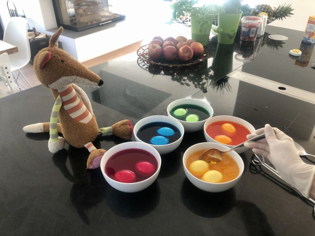 Mama taucht alle Eier behutsam in der Farbe